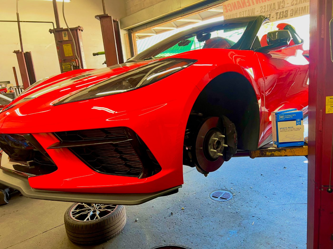Red Chevrolet Corvette C8 on a lift for brake service