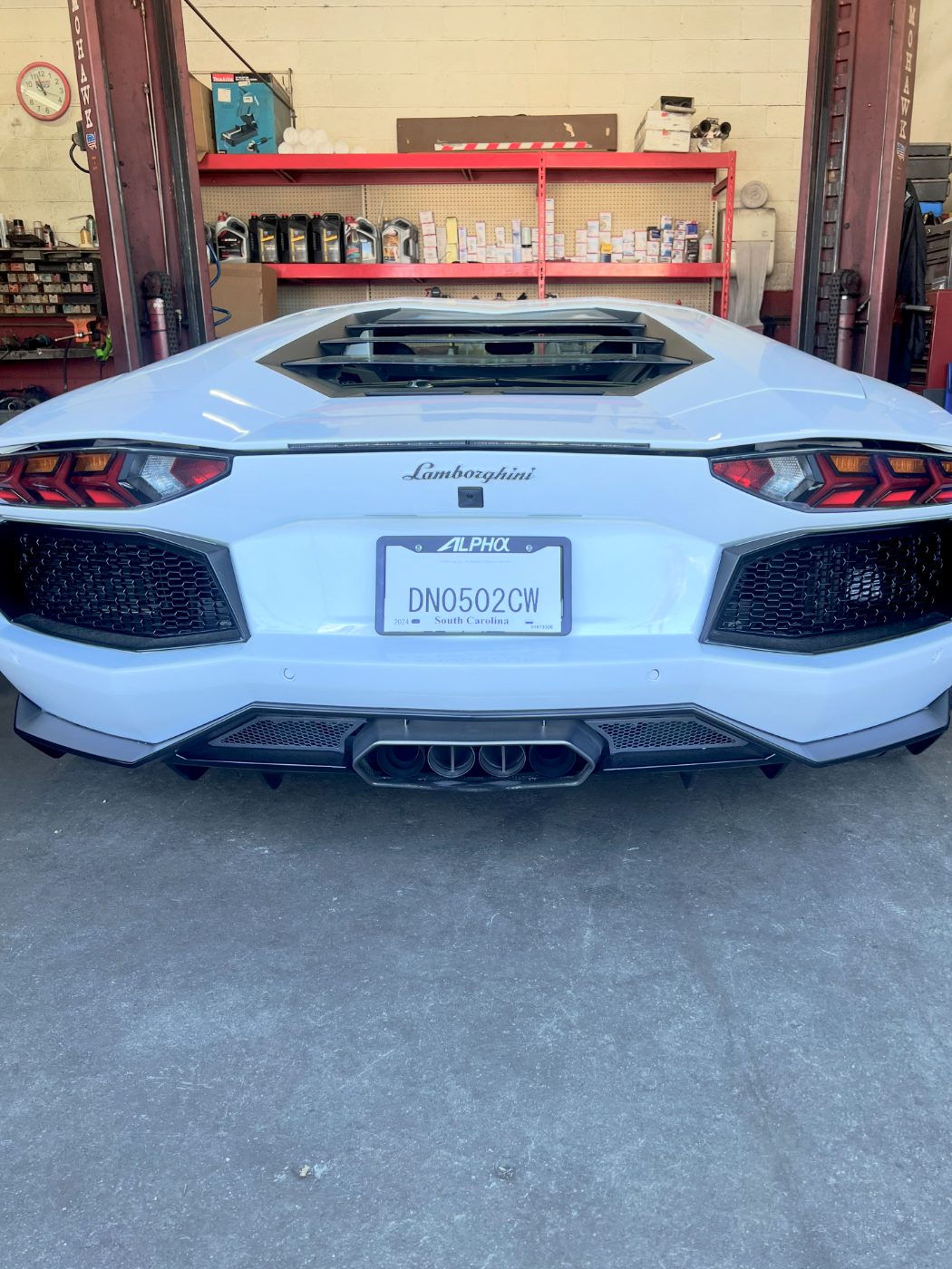 White Lamborghini Aventador on a lift inside the shop